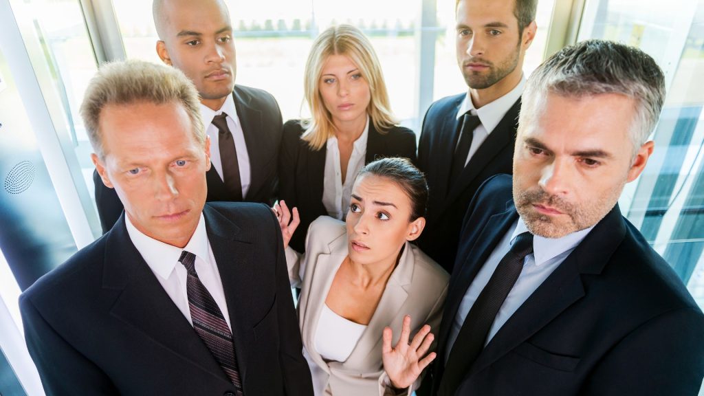 A woman surrounded closely by people in an elevator