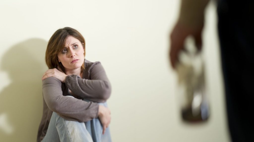 A domestic violence victim with a black eye sitting on a floor