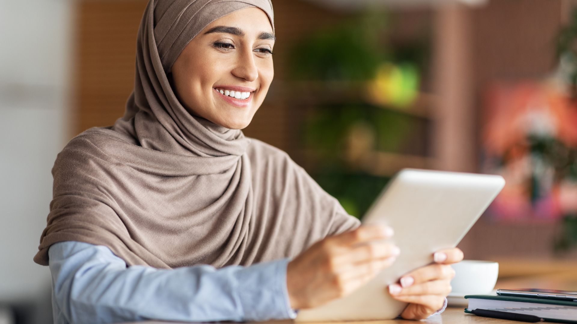 A happy looking woman smiles while looking at her tablet computer