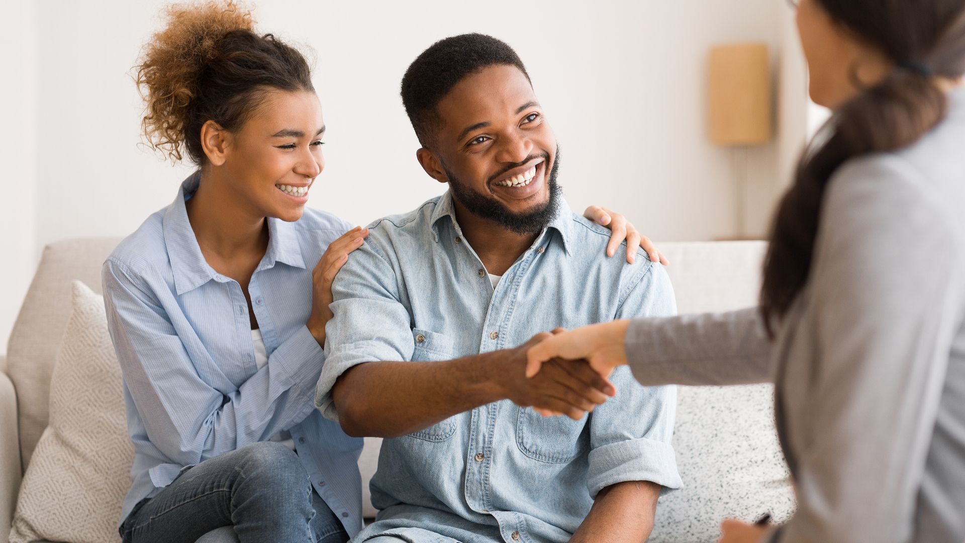 A smiling man shakes his therapist's hand while his girlfriend smiles on and rests a hand on his shoulder