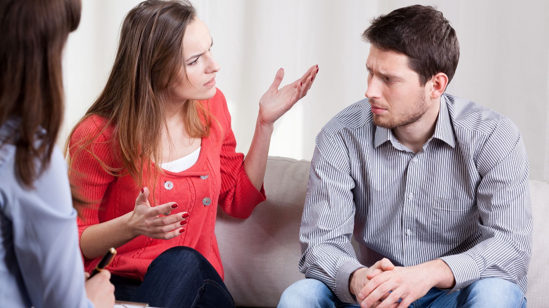 A couple on a couch argue while their therapist looks on