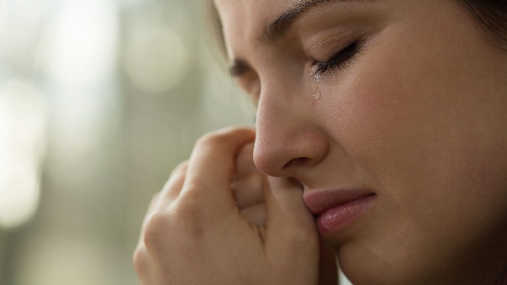 A close up image of a woman crying in grief
