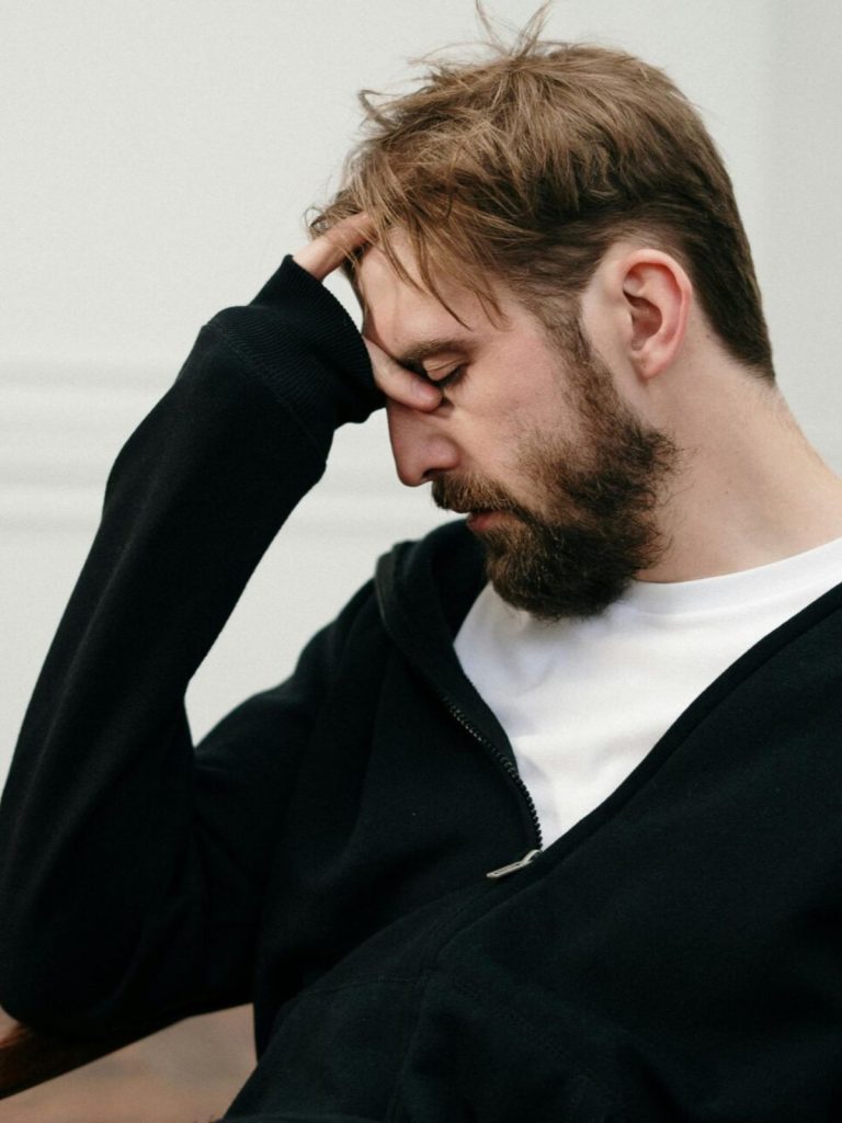 Image Of Frustrated Man With His Hand On His Forehead. He Is In A Black Hoodie With A White Shirt. Therapy Services In Glendale, Ca - Dr. Taji Huang Ph.d.